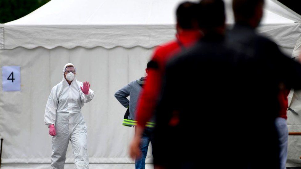 Workers queue for a coronavirus test at a testing station on the factory premises of the Westfleisch meat processing company in Hamm, western Germany, 10 May 2020