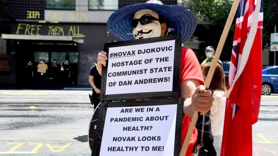An anti-vax protester holds a sign supporting Novak Djokovic