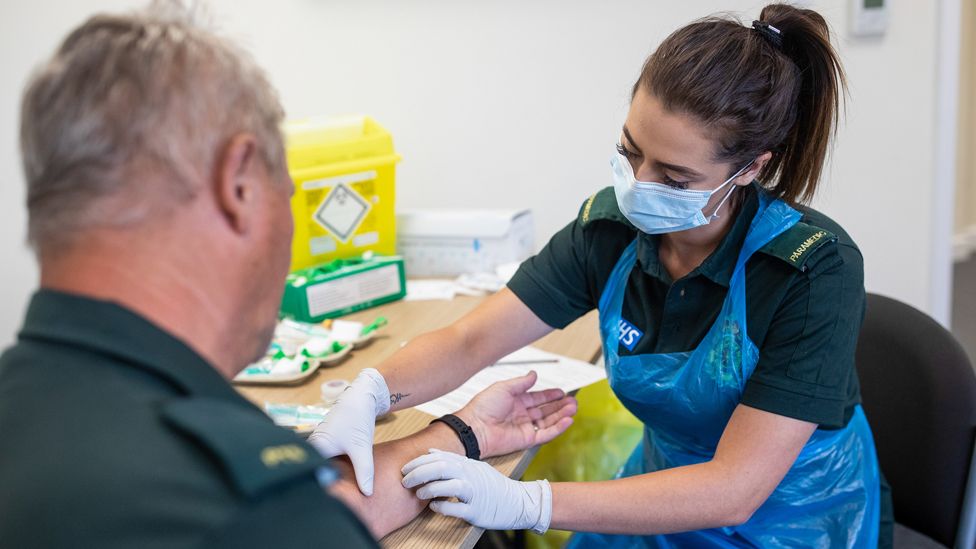 A paramedic takes a blood sample from a front line ambulance worker