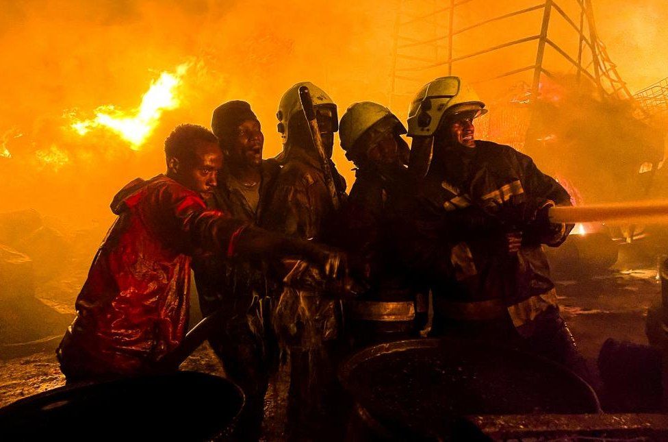 Firefighters and volunteers attempt to extinguish a fire that broke out at a commercial depot, used for oil barrels and flammable drums, near Muthurwa settlement, in Nairobi, Kenya, January 30, 2024