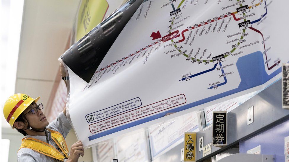 Man replaces a map with train fares