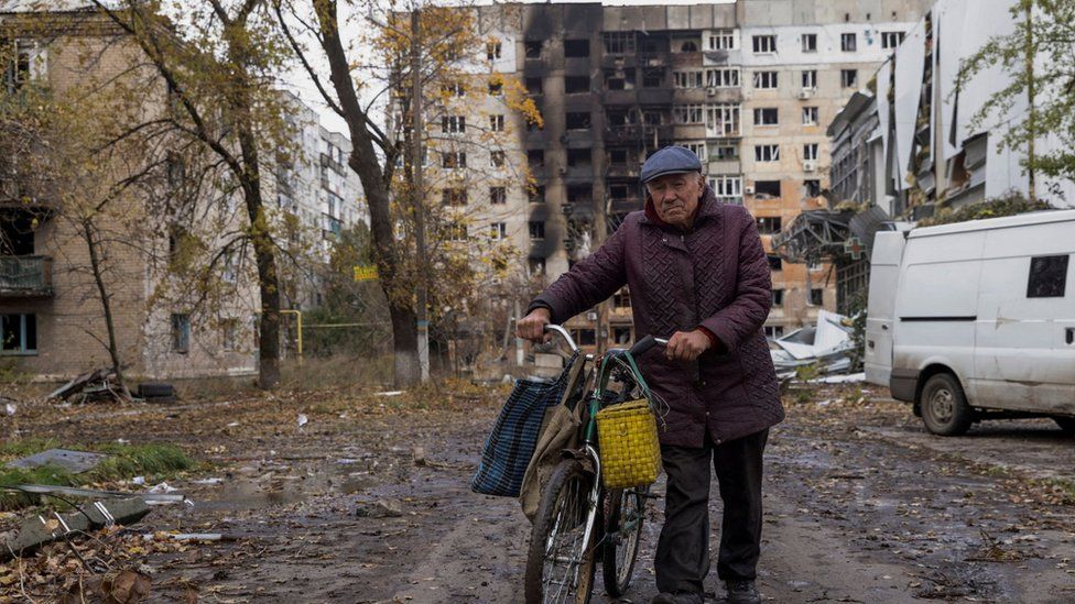 A man walks with his bicycle in front of bombed-out residential buildings in Avdiivka, eastern Ukraine. Photo: October 2023
