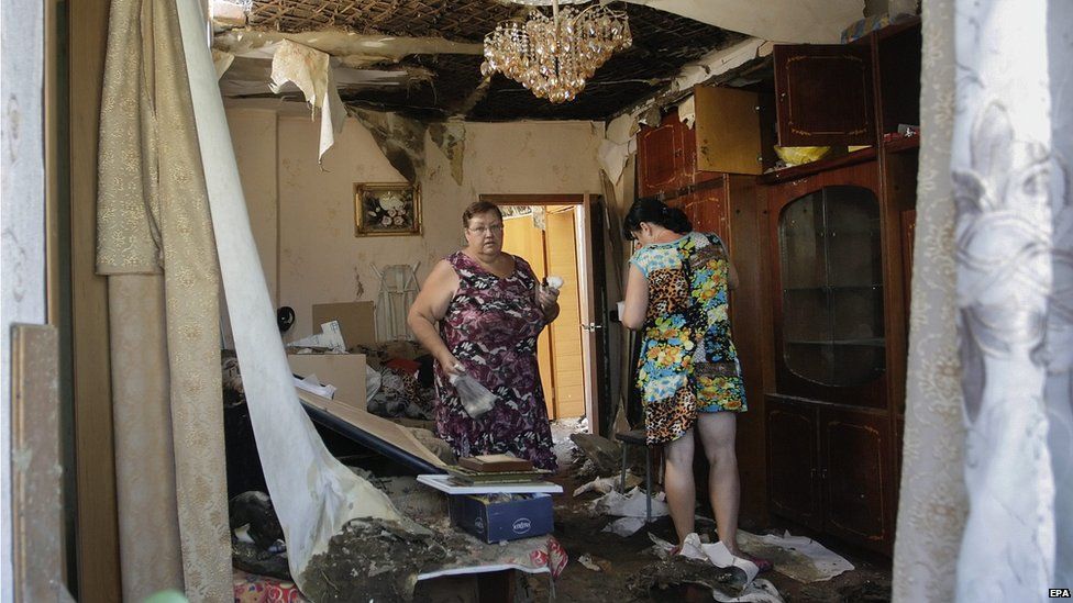 Local people react as they return to home that was damaged during a shelling, in Donetsk, Ukraine, 2 August 2015