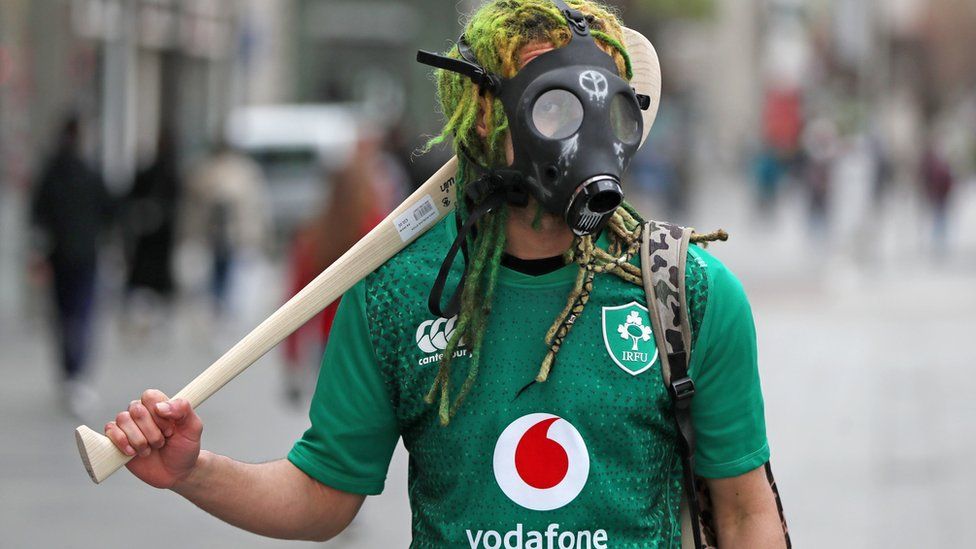 A man wearing a gas mask and carrying a hurling stick in Dublin on St Patrick's day