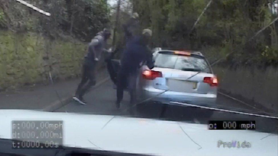 Des délinquants lançant des pierres sur une voiture de patrouille de police