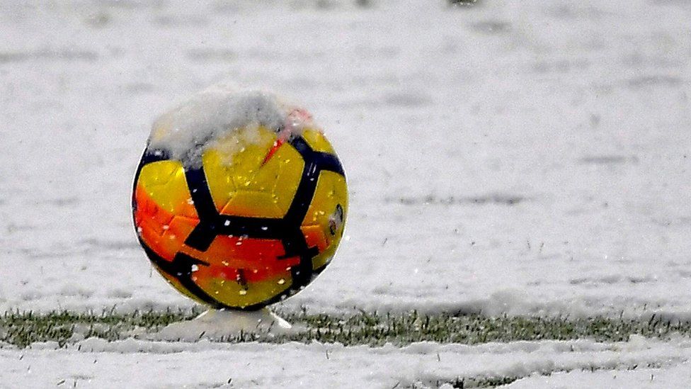 Yellow and orange football on a snowy pitch