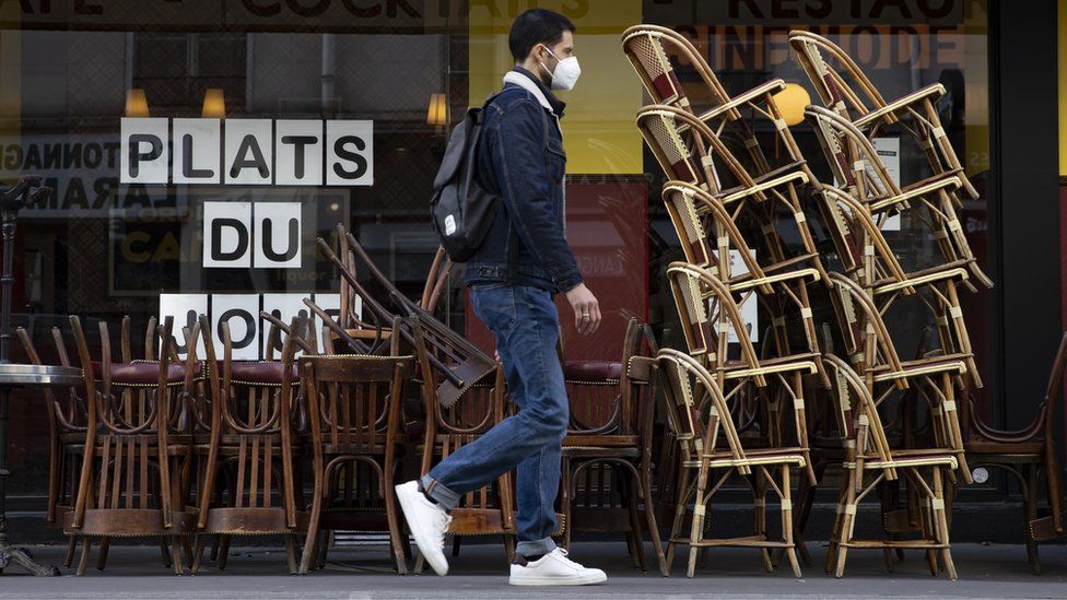 A man walks by an empty cafe in Paris