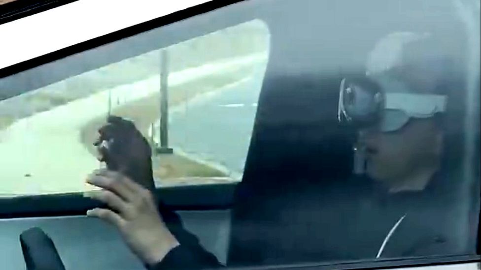 Screenshot from the video of someone with their hands off the steering wheel while wearing the Apple headset