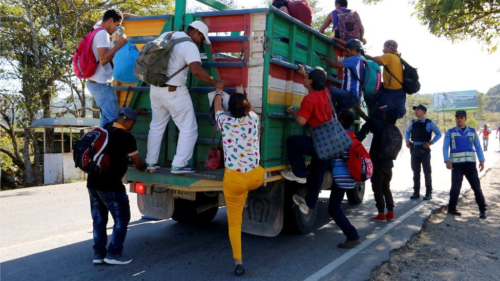 Hondurans climb onto a truck to continue their journey toward the United States