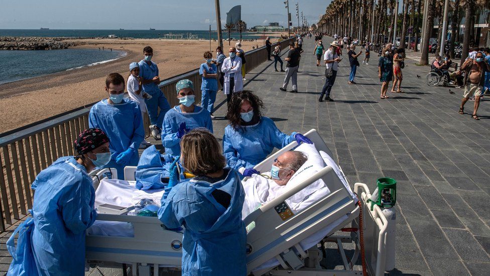 A hospital patient lying in a bed is taken to the seaside by a group of intensive health care staff