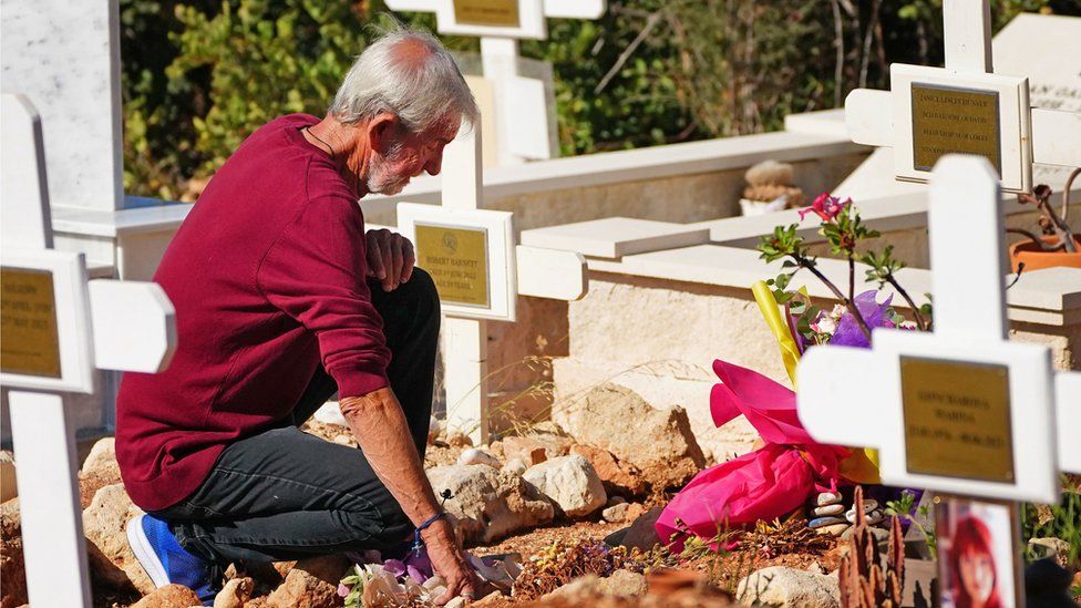 A man lays flowers on a grave