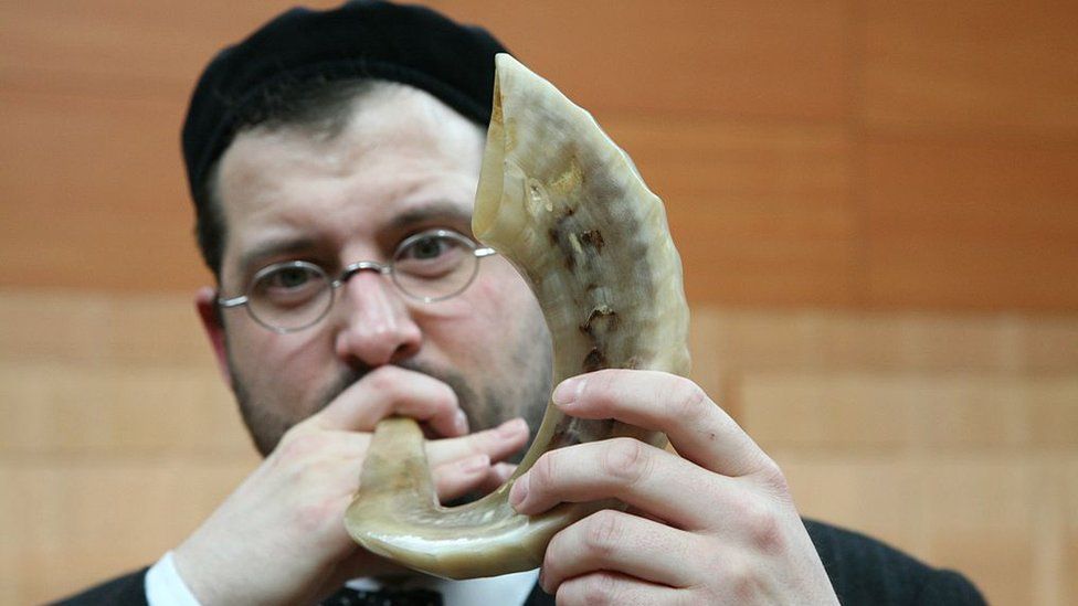 Man blowing a shofar in a synagogue