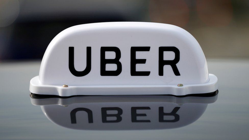 The logo of taxi company Uber is seen on the roof of a private hire taxi