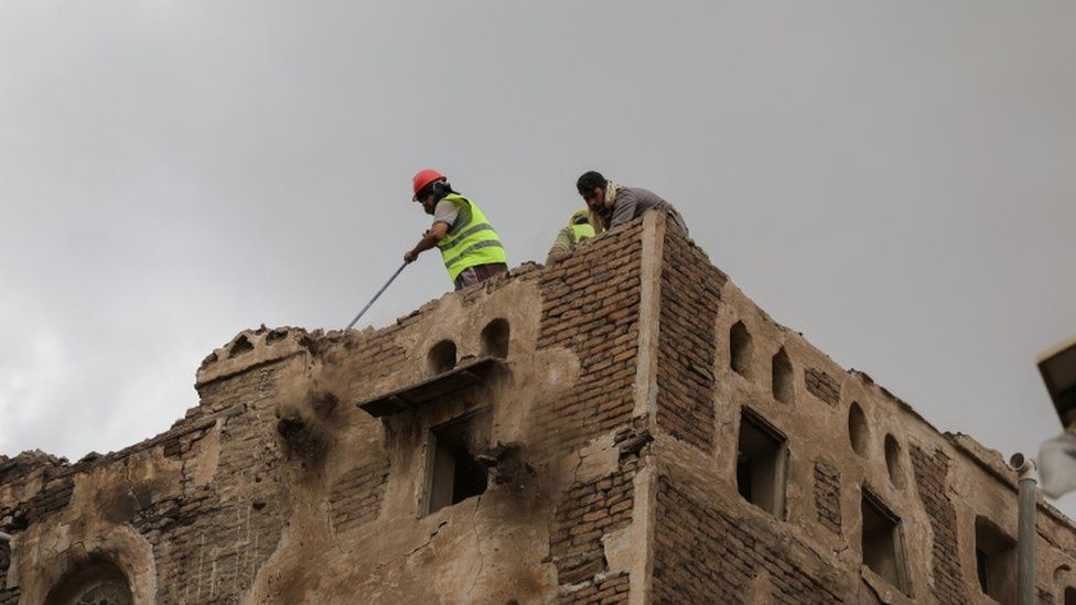 Workers demolish a building damaged by rain in Sanaa