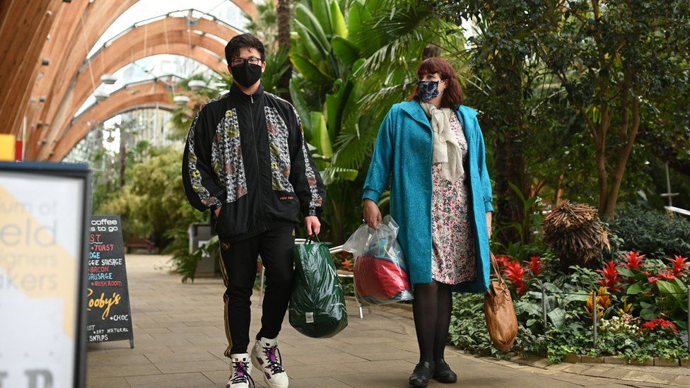 A couple wearing protective face masks, walk through The Winter Garden in Sheffield, in northern England on October 21, 2020