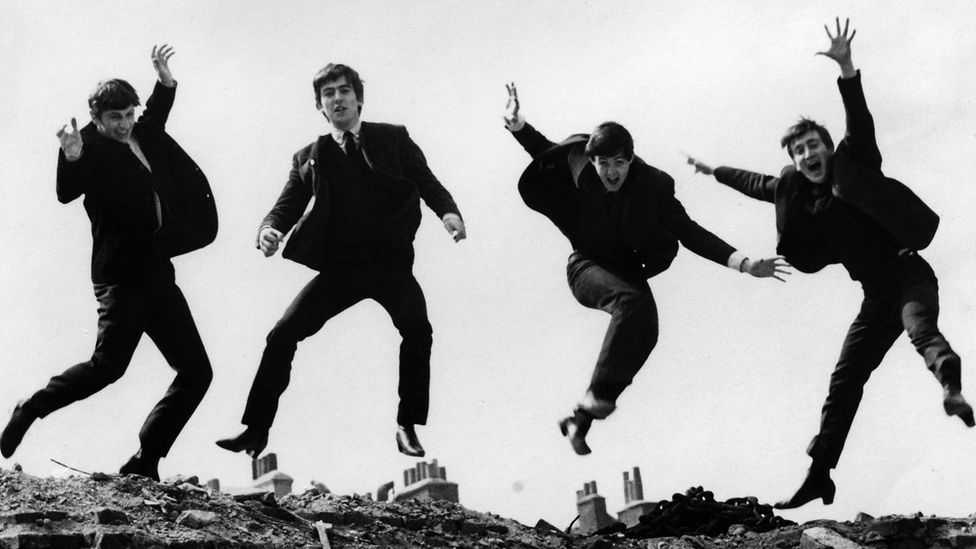 The Beatles leaping on a wall