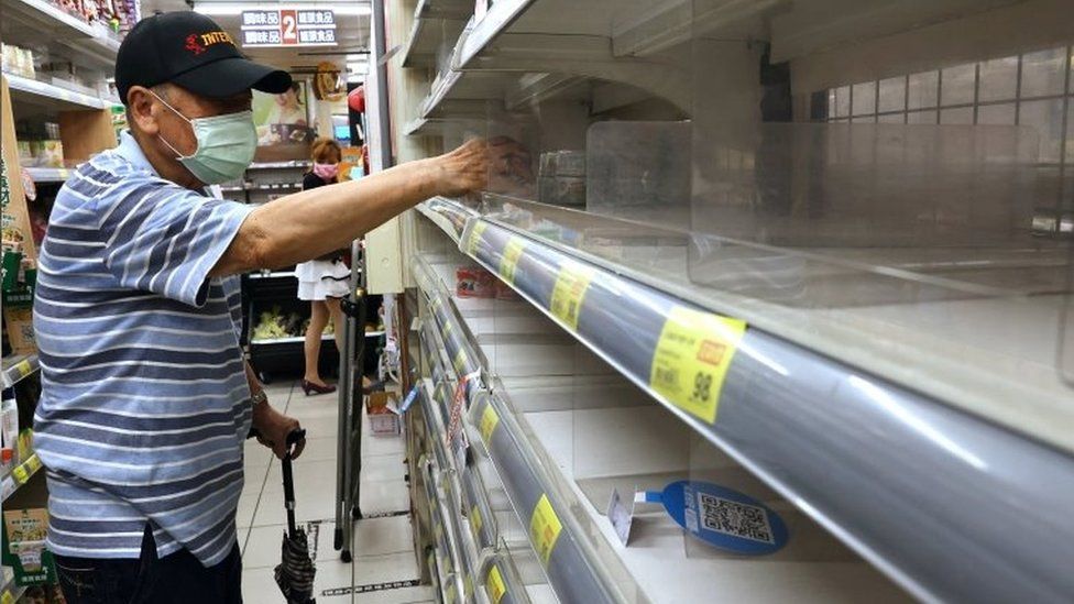 A man takes instant noodles from a near-empty shelf in a supermarket in Taipei, Taiwan. Photo: 16 May 2021