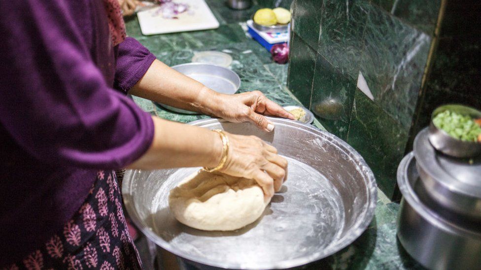 Una donna prepara l'impasto per il tradizionale pane indiano chapati nella cucina della tenuta del tè di Boisahabi, Assam, India, il 7 marzo 2019.