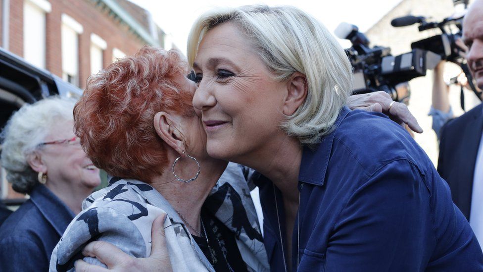 Marine Le Pen greets supporters as she leaves the polling station after casting her vote in Henin Beaumont.