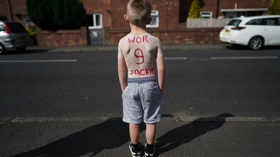 A youngster has "Wor Jackie" and the number 9 painted on his back