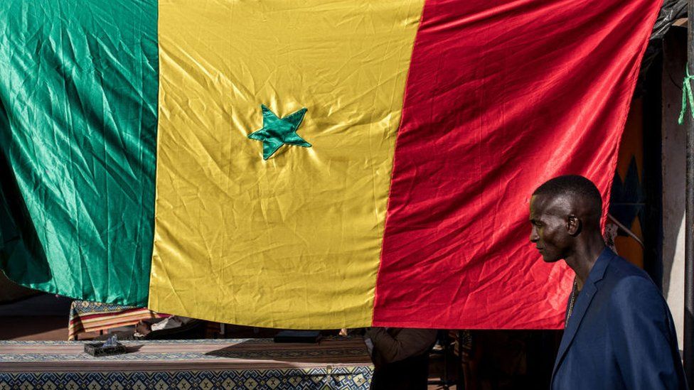 A man walks past a Senegalese flag in the run-up to the election.