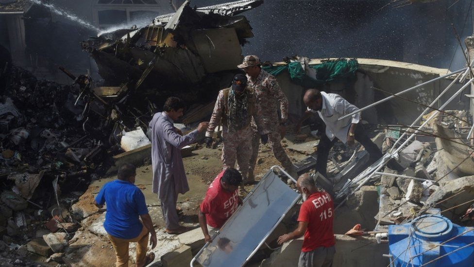 Rescue workers gather at the site after a Pakistan International Airlines flight crashed in a residential neighbourhood