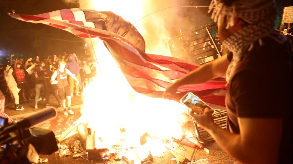 Protesters burn a US flag during a rally against the death in Minneapolis police custody of George Floyd, in Washington, DC, 31 May 2020