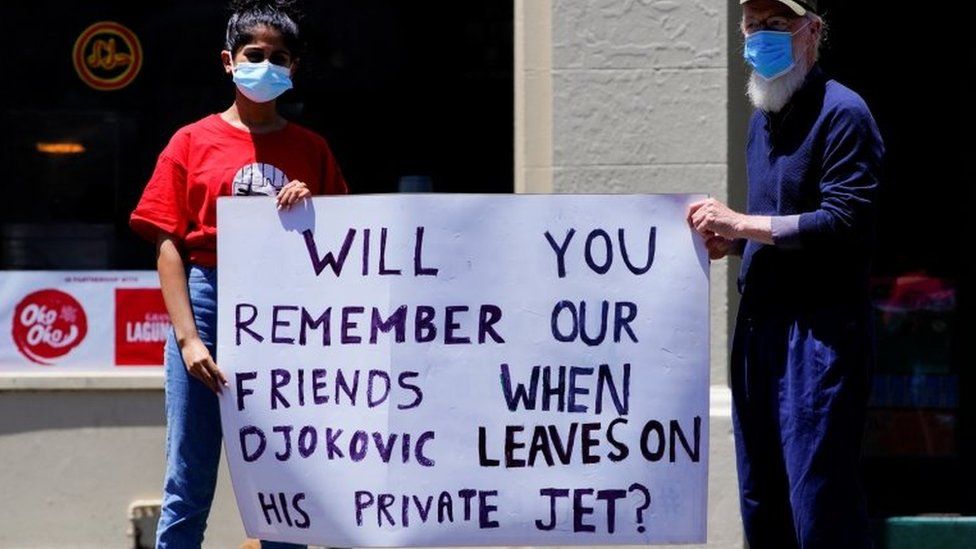 Активисты-беженцы держат плакат с надписью: «Будете ли вы вспоминать наших друзей, когда Джокович улетит на своем частном самолете?»