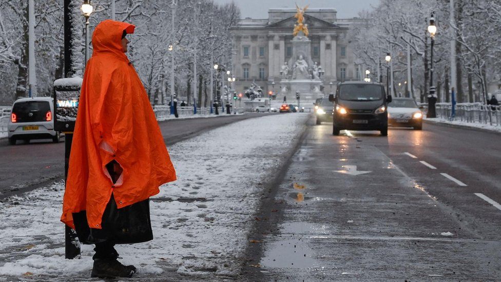 A person dressed in an orange coat stands on an icy Mall