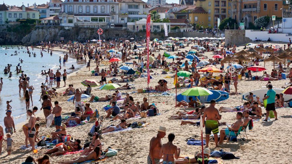 Beachgoers crowd Praia da Duquesa in Cascais, Portugal