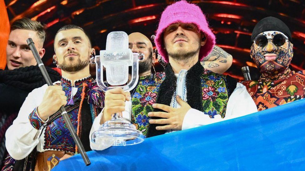 Members of the band Kalush Orchestra pose on stage with the winner's trophy and Ukraine's flags after their Eurovision win