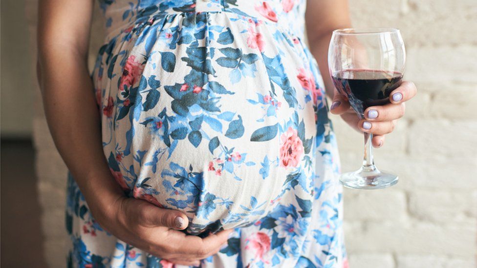 Pregnant woman holding a wine glass