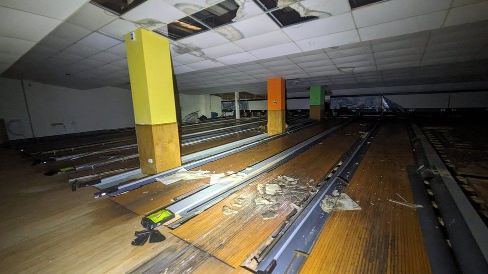 Bowling lanes with damaged ceiling tiles. Photo is taken in the dark.