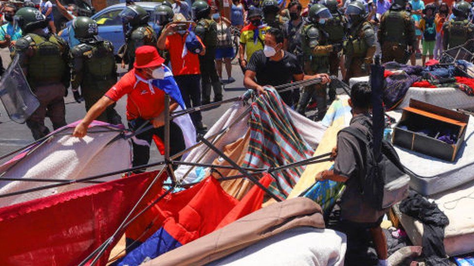 People destroy a makeshift camp of migrants during a protest in Iquique, Chile, 30 January 2022