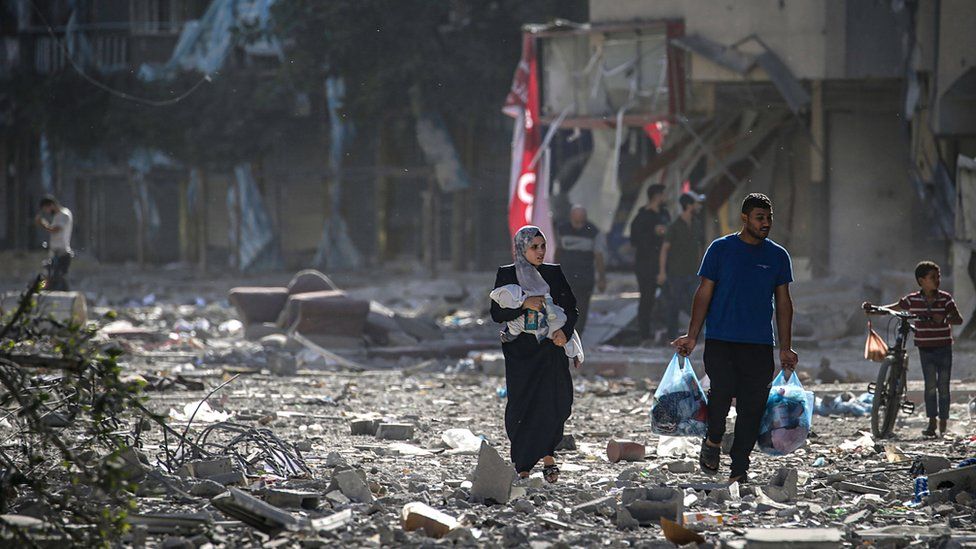 People walk through a destroyed street in Gaza City