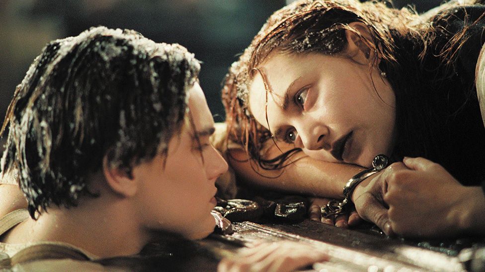 Titanic film characters Jack and Rose floating in the sea holding on to wooden door panel