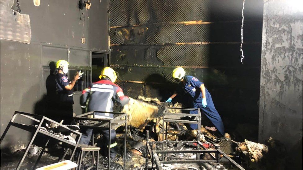 Rescue officials pick through the blackened remains of the venue in Sattahip district in Chonburi, Thailand