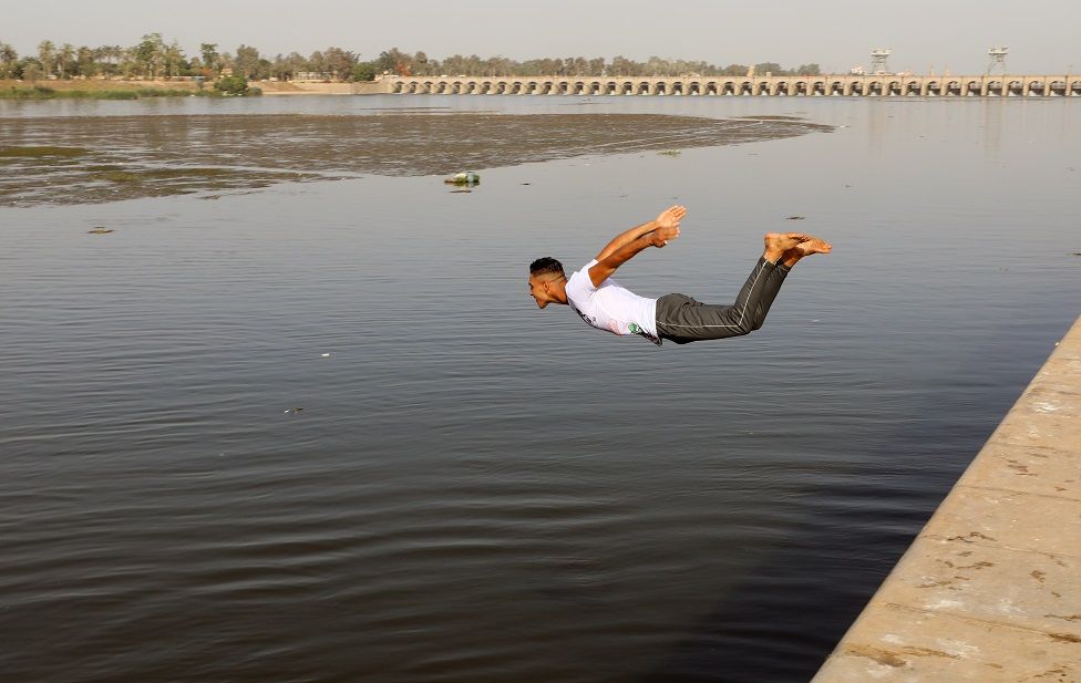 A young Egyptian jumps into the water of the Nile river during hot weather in the Qanater neighbourhood on the outskirts of Cairo, Egypt.
