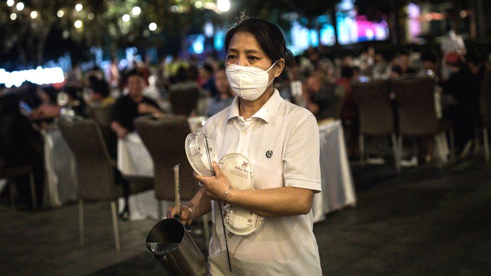 A waiter wears a protective mask while serving on the open platform of the Sheraton hotel on May 28.2020 in Wuhan, China.