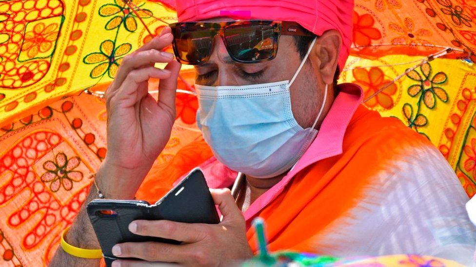A traditionally dressed Indian fan looks at his mobile phone on the third day of the third cricket Test match between Australia and India at the Sydney Cricket Ground (SCG) in Sydney on January 9, 2021. (Photo by SAEED KHAN / AFP) / -- IMAGE RESTRICTED TO EDITORIAL USE - STRICTLY NO COMMERCIAL USE -- (Photo by SAEED KHAN/AFP via Getty Images)