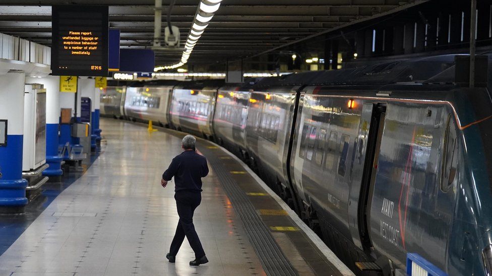 A man stands in a quiet Euston train station