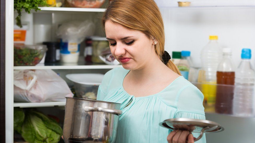 woman smelling pot of food