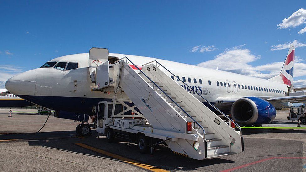 A British Airways plane with boarding steps beside it