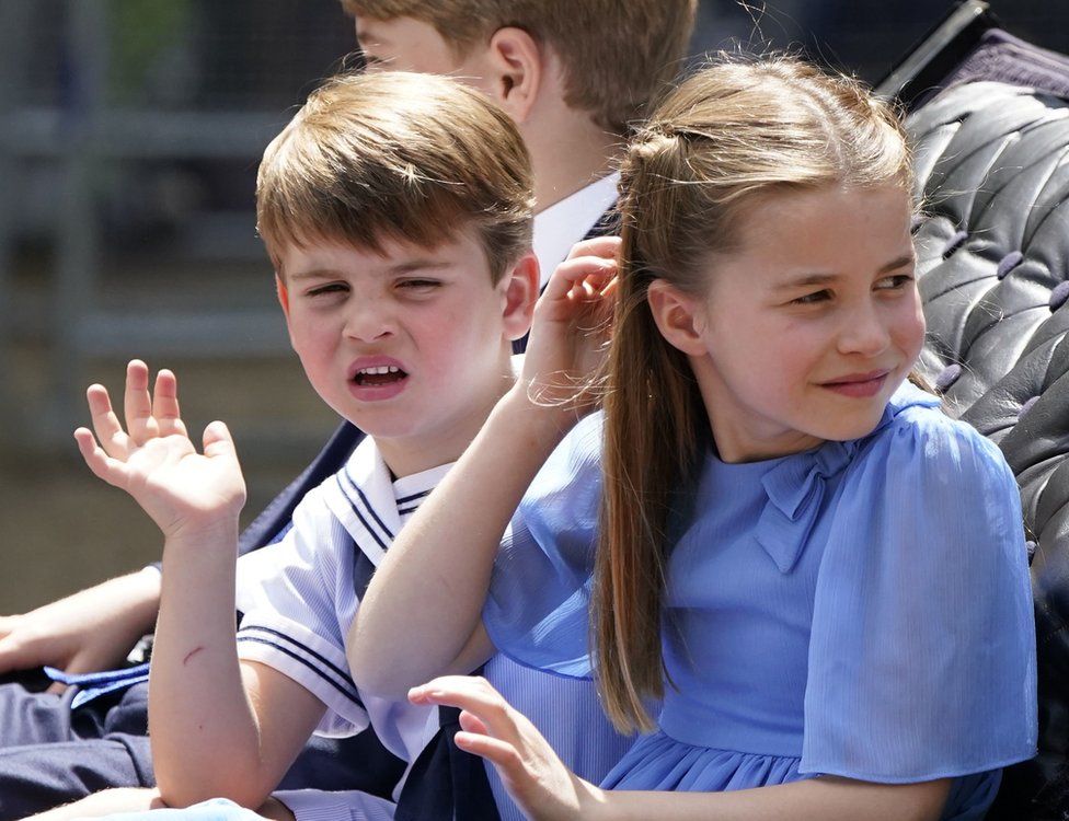 Prince George, Prince Louis, and Princess Charlotte wave ride in a carriage as the Royal Procession travels down The Mall to the Trooping the Colour ceremony