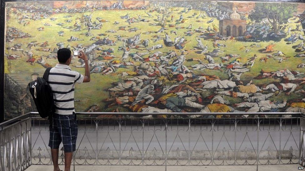 An Indian man takes a photograph of a painting depicting the Jallianwala Bagh massacre in Amritsar on April 12, 2011