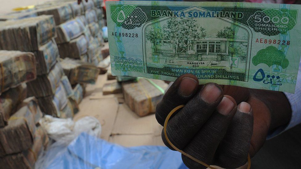 A man holds a 5,000-Somaliland shilling banknote.