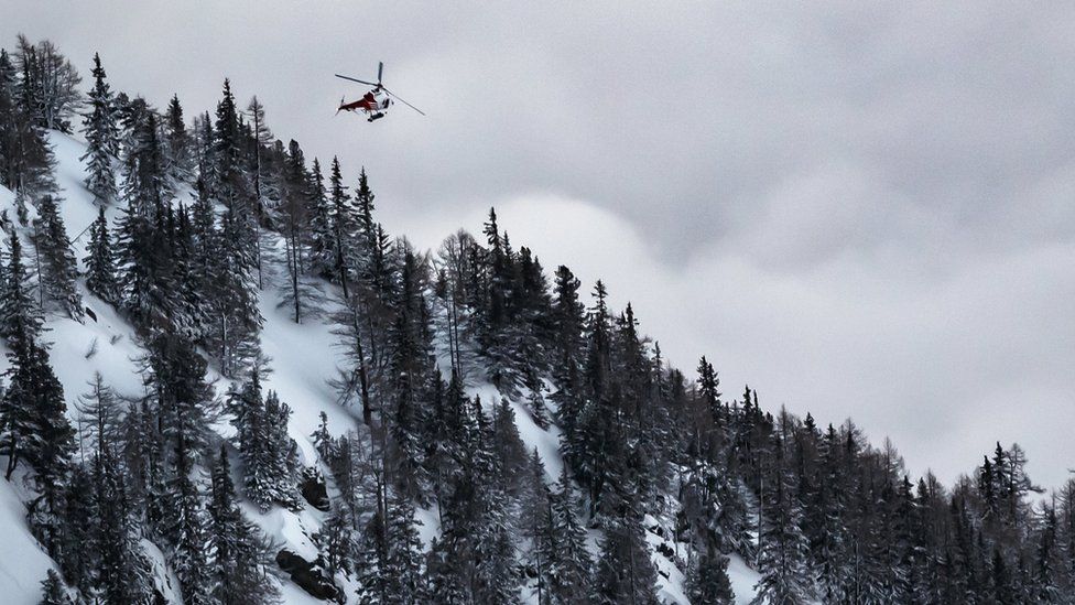 A rescue helicopter leaves the location of an avalanche after two people were swept away in Switzerland, 18 February 2018