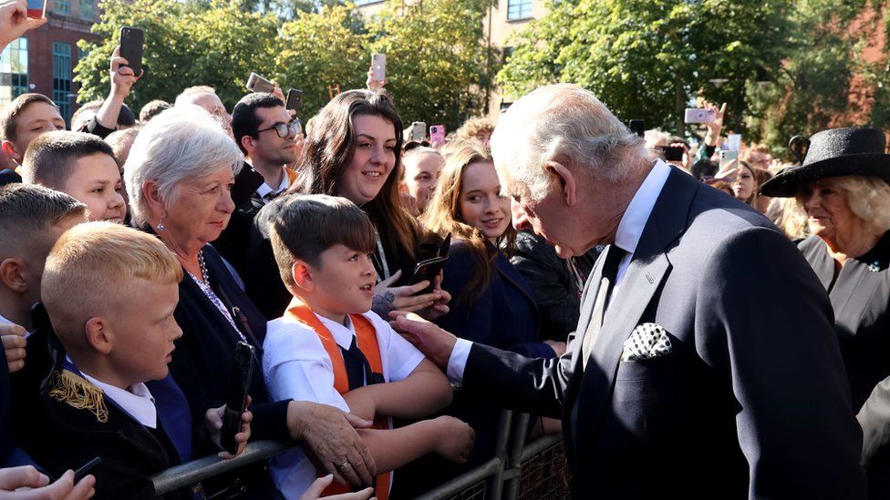 King Charles speaks to a young boy among the crowd of people outside St Anne's Cathedral
