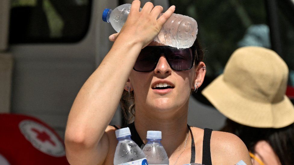Женщина охлаждается водой в бутылках в Афинах, Греция. Фото: 20 июля 2023 г.
