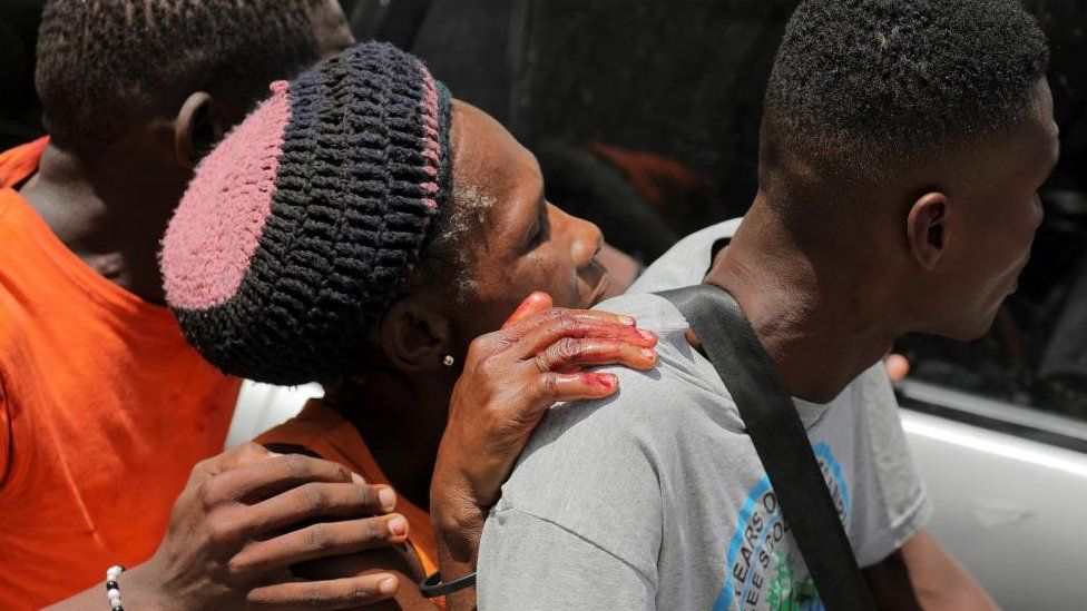 People take a wounded woman to a hospital after gangs took over their neighbourhood Carrefour Feuilless, in Port-au-Prince, Haiti August 15, 2023.